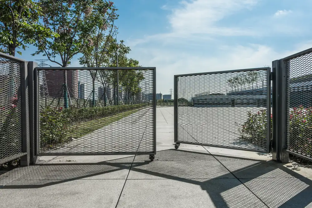Black metal automatic swing gate across a residential driveway