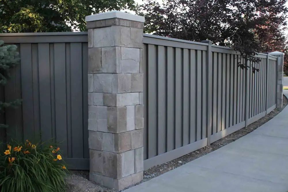 Gray horizontal composite fence boards alongside a stone wall