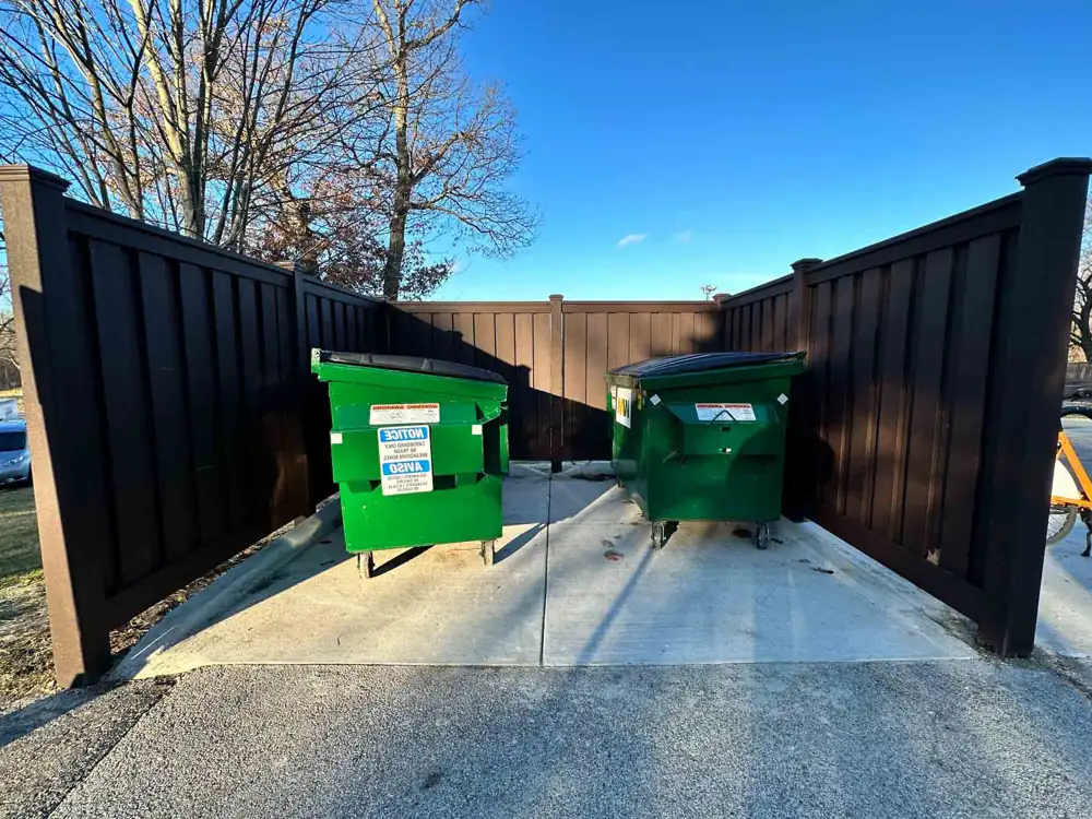 Black metal dumpster enclosure with solid panels and gates