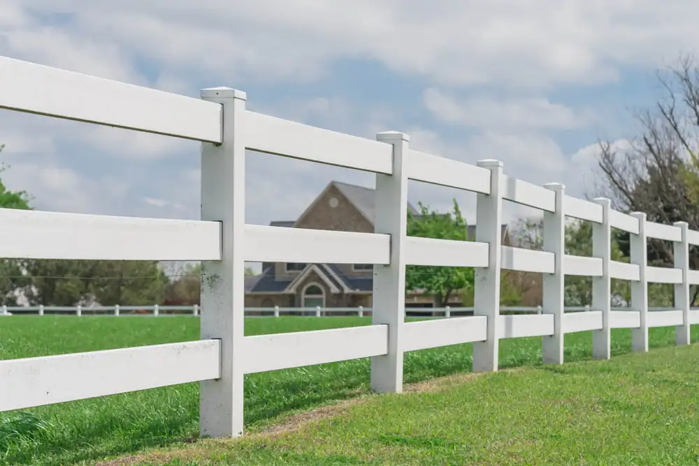 White post-and-rail fence running along a green lawn